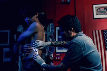 Close-up hands of master Tattoo artist in white gloves sticking paper with pattern on client hand...