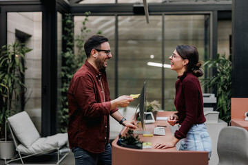 Smiling business people, standing on the reception, looking at each other.