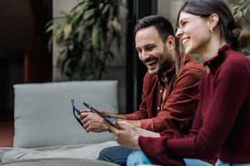 Smiling business people sitting next to each other, working online, using a tablet.