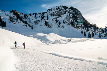 Naklejka na ściany i meble Schneeschuhlaufen im Winter. Ein Paar in den Bergen in einer verschneiten Winterlandschaft. Wintersport ausüben in der Schweiz.