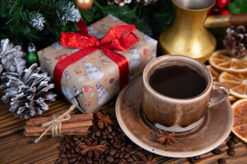Fototapeta na wymiar Christmas mood, holiday atmosphere. Red cup of coffee, fir branches with cones, Christmas gifts, star anise on a wooden table background.