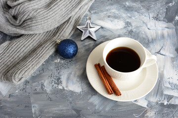 cup of coffee with cinnamon, christmas sphere and star on grey background