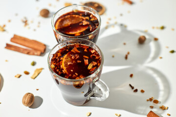 Cup with Christmas mulled red wine with spices and oranges on a white background hard light,...