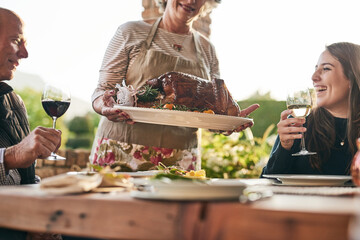 Thanksgiving, food and family with a woman carrying a turkey during a dinner party outdoor for...