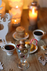 Two types of cookies, cups of tea or coffee, various Christmas decorations and lit candles. Cozy Christmas atmosphere at home. Selective focus.