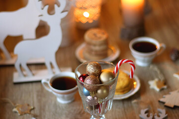 Two types of cookies, cups of tea or coffee, various Christmas decorations and lit candles. Cozy Christmas atmosphere at home. Selective focus.