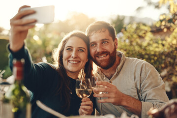 Wine, phone and couple take a selfie with a toast to a happy marriage and share romantic content on social media. Woman smiles taking pictures on a date with a lovely partner drinking champagne