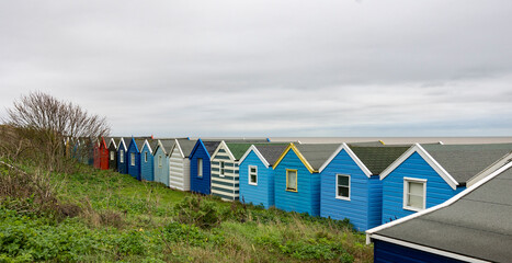 Naklejka premium A row of colourful beach huts under a blue sky at Southwold beach in England
