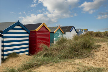 Fototapeta na wymiar A row of colourful beach huts under a blue sky at Southwold beach in England