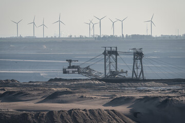 View of surface mine in Germany, heavy machinery in lignite mine and wind turbines in the background