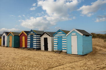 Fototapeta na wymiar A row of colourful beach huts under a blue sky at Southwold beach in England
