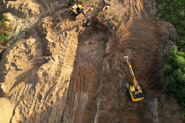 Excavator on earthmoving at construction site, aerial view. Excavator on earthworks. Open pit development and sand mining. Loader digg ground, top view. Earthmover and digger on groundwork in quarry..