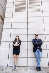 Un uomo e una donna vestiti eleganti si appoggiano al muro di una struttura moderna