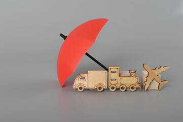 Red umbrella and wooden toy vehicles. Vehicle insurance, warranty, repair, financial, banking and money concept