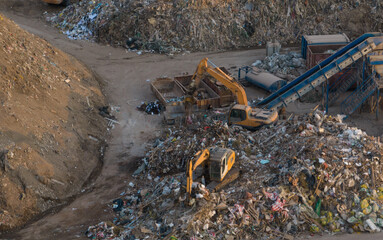 Landfill with Construction waste (CDW). Trash disposal for recycling and re-use. Excavator log grab crane on landfill. Recycling of Construction waste or debris. Secondary raw. Wood Waste Recycling..