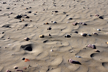 Stones on sand at beach. Sea stones background at seashore. Colored stone on coastline. Stone on sand background at sea beach. Pebbles at coast. Pebble as abstract natural background. Sea stones. .