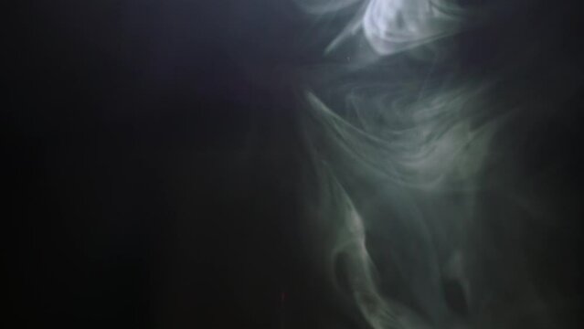 a lamp illuminates billows of smoke in a dark room. close-up