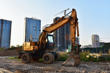 Excavator on earthmoving at construction site. Earth-Moving Heavy Equipment. Backhoe Loader. House and Building construction. Renovation program. Bucked wheel excavator at construction site.