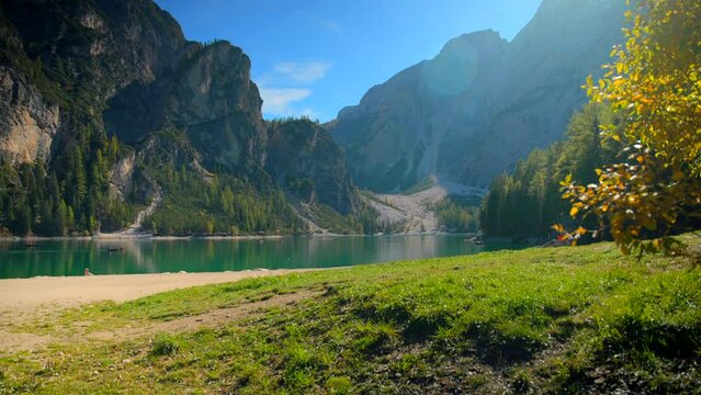 Footage at Lago di Braies, up the mountains in European Alps in Italian Dolomites. Video of a glaciar lake, boats, forest  filmed by the lake in 4k with a camera on a gimbal with smooth movement
