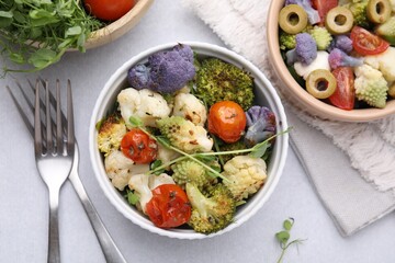 Delicious salad with cauliflower and tomato served on white table, flat lay