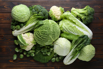 Many different types of fresh cabbage on wooden table, flat lay