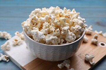 Tasty popcorn on light blue wooden table, closeup