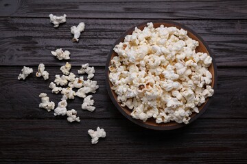 Tasty popcorn on black wooden table, flat lay