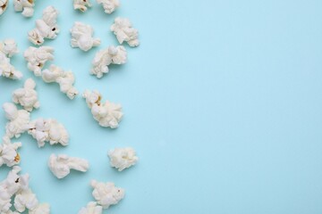 Tasty popcorn on light blue background, flat lay. Space for text