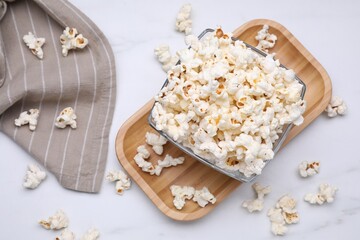 Bowl of tasty popcorn on white table, flat lay