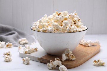 Bowl of tasty popcorn on white table