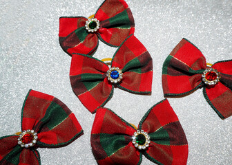 five Christmas red and green dog bows lie on a shiny gray background. view from above. accessories...