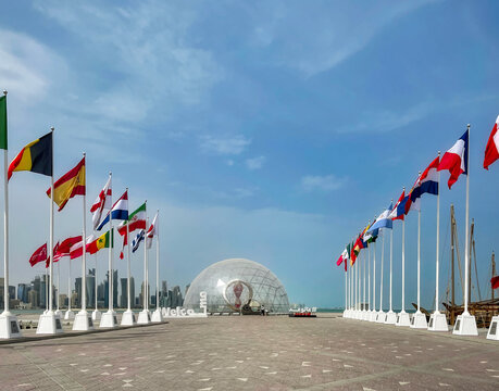DOHA, QATAR - April 13, 2022: Perspective view of the dome with the countdown clock at Doha Corniche, Qatar. On both sides are the flags of nations qualified for the World Cup Qatar 2022.
