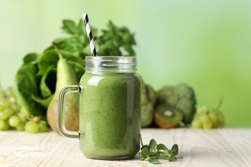 Mason jar of fresh green smoothie and ingredients on wooden table