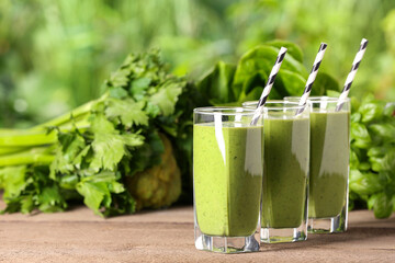 Glasses of fresh green smoothie and ingredients on wooden table outdoors, space for text