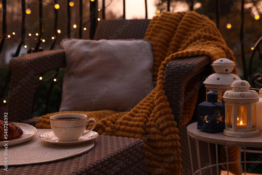 Wall mural Beautiful view of garden furniture with pillow, soft blanket and coffee at balcony