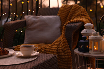 Beautiful view of garden furniture with pillow, soft blanket and coffee at balcony