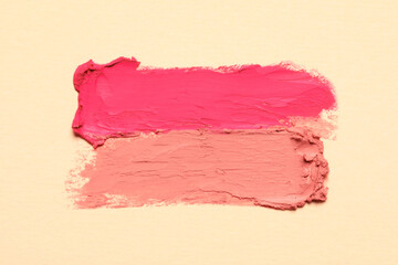 Smears of beautiful lipsticks on beige background, top view
