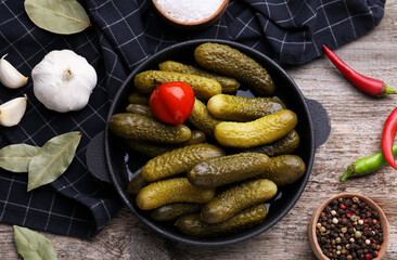 Pickled cucumbers and ingredients on wooden table, flat lay