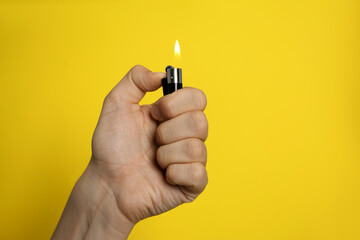 Man holding lighter on yellow background, closeup. Space for text