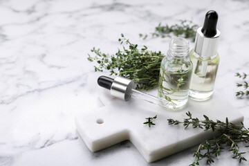 Thyme essential oil on white marble table, space for text