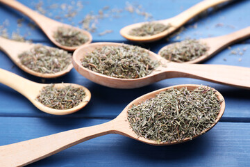Spoons with dried thyme on blue wooden table, closeup