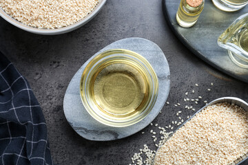 Sesame oil and seeds on dark grey table, flat lay