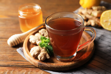 Cup of delicious ginger tea and ingredients on wooden table