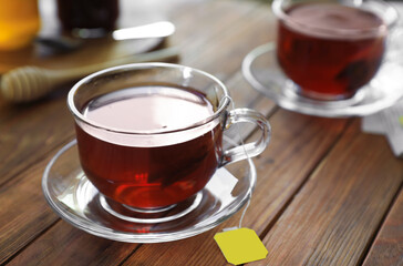 Tea bag in glass cup on wooden table, closeup. Space for text