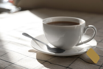 Bag of black tea in cup on table