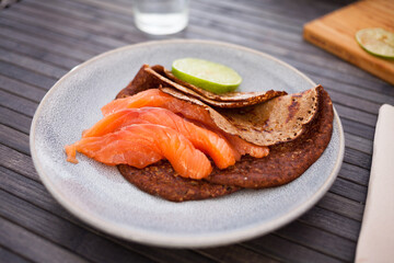 healthy breakfast of pieces of salted smoked salmon with buckwheat pancakes and lime
