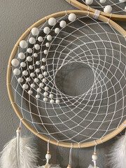 Close-up white feathers dreamcatcher craft on gray background