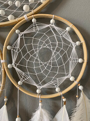 Close-up white feathers dreamcatcher craft on gray background
