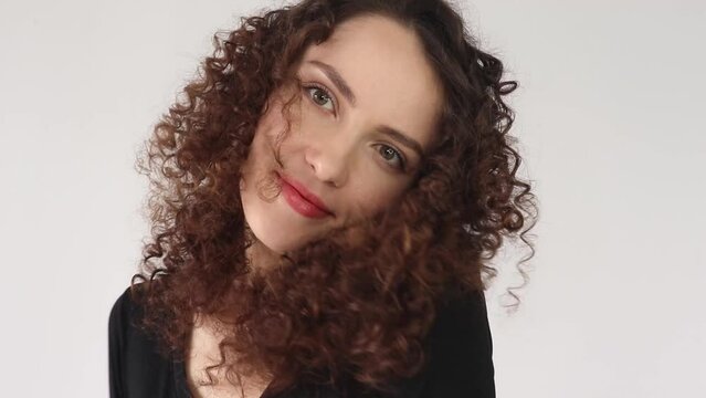 Curly brunette girl after perming her hair. White woman with fine curls, on white background in close-up. After a perm treatment
