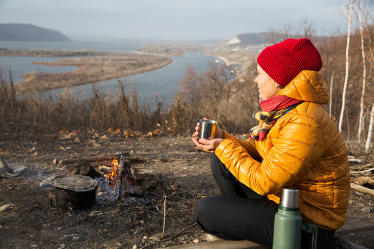 woman drink tea sitting near a bonfire in the fall in nature. mental health. Slow life. Enjoying the little things. Lykke concept 